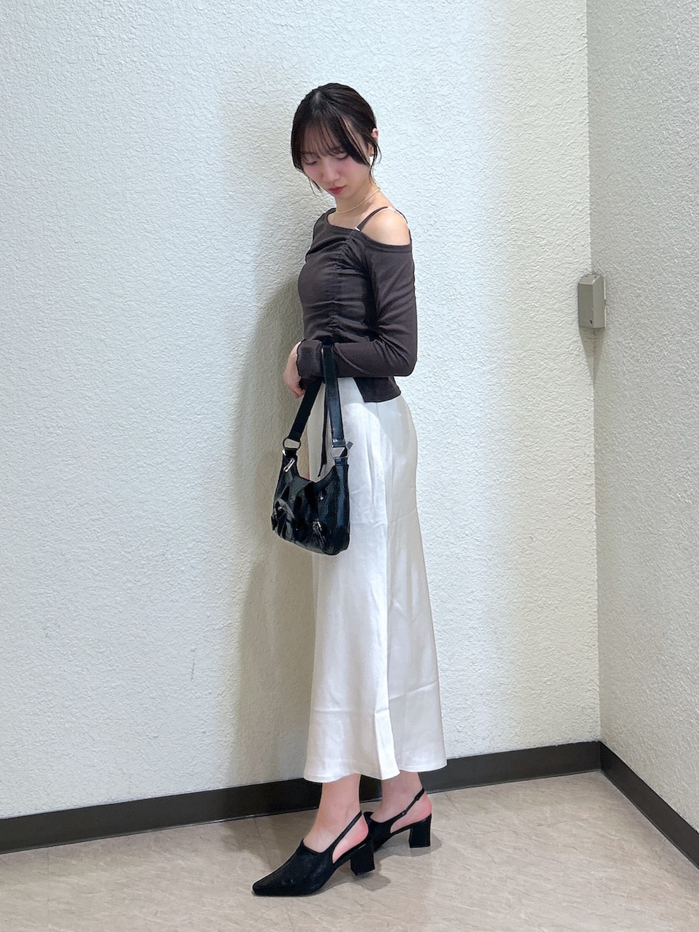 ブラウン系のTシャツ/カットソー、ホワイト系のスカート、ブラック系のパンプスを着用したレディースの秋コーディネートの2枚目の写真