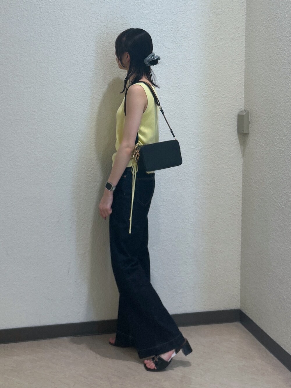 イエロー系のニット/セーター、ブルー系のデニムパンツ、ブラック系のショルダーバッグを着用したレディースの夏コーディネートの2枚目の写真