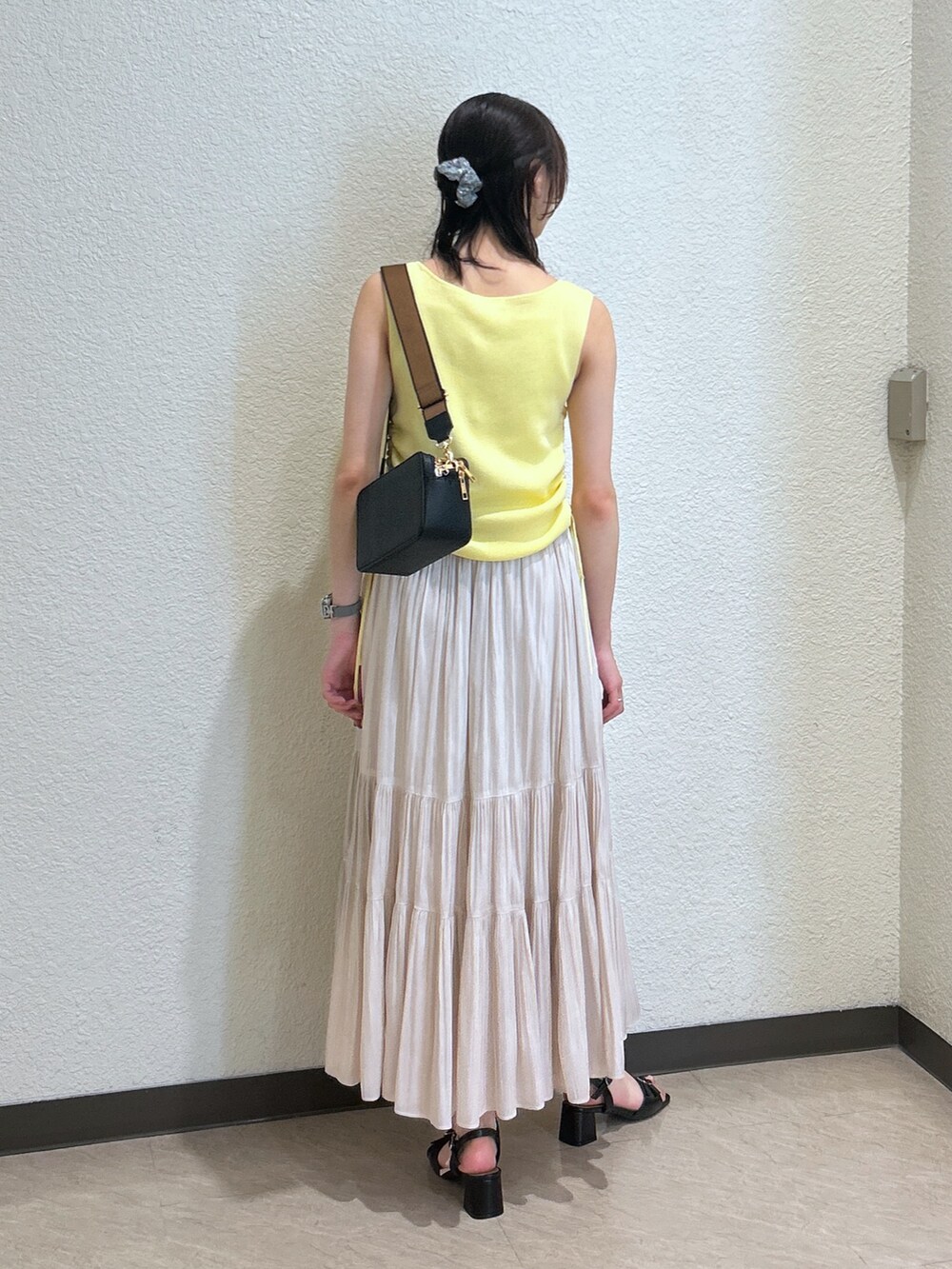 イエロー系のニット/セーター、ホワイト系のスカート、ブラック系のサンダルを着用したレディースの夏コーディネートの3枚目の写真