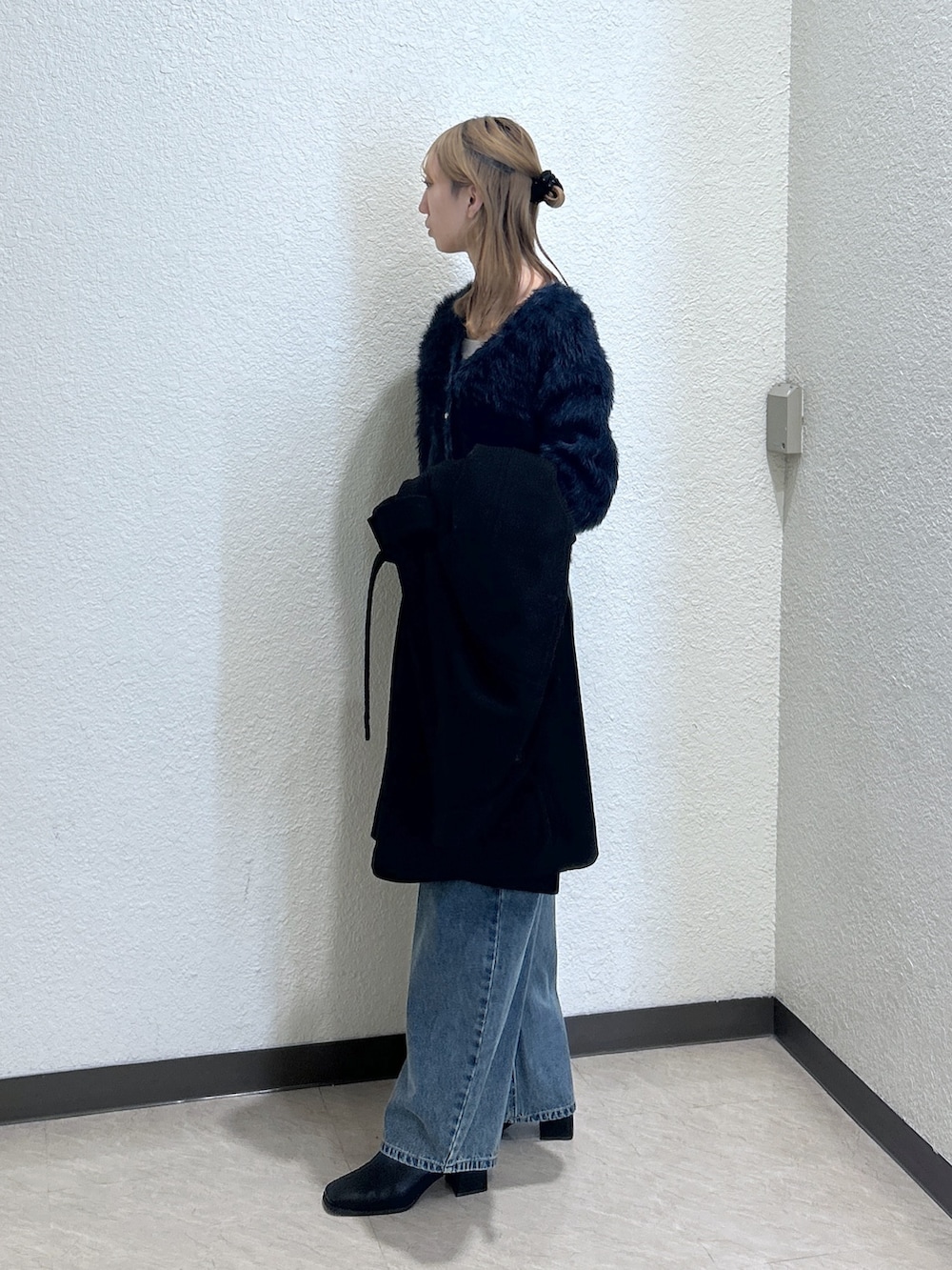 ブルー系のニット/セーター、ブラック系のステンカラーコート、ブラック系のブーツを着用したレディースの秋コーディネートの3枚目の写真