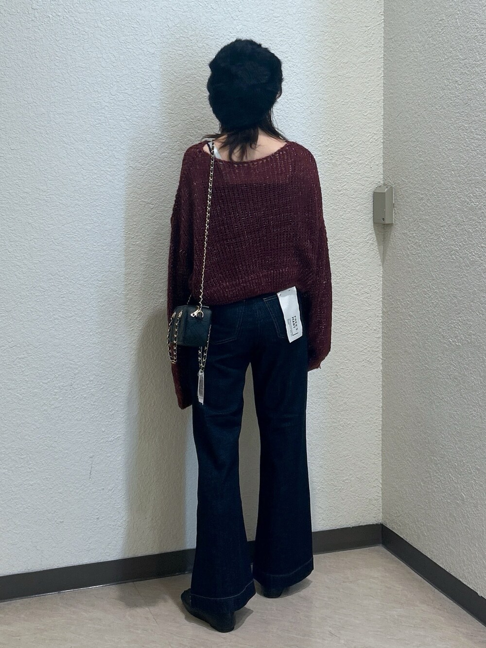 レッド系のニット/セーター、ブルー系のデニムパンツ、ブラック系のショルダーバッグを着用したレディースの秋コーディネートの3枚目の写真