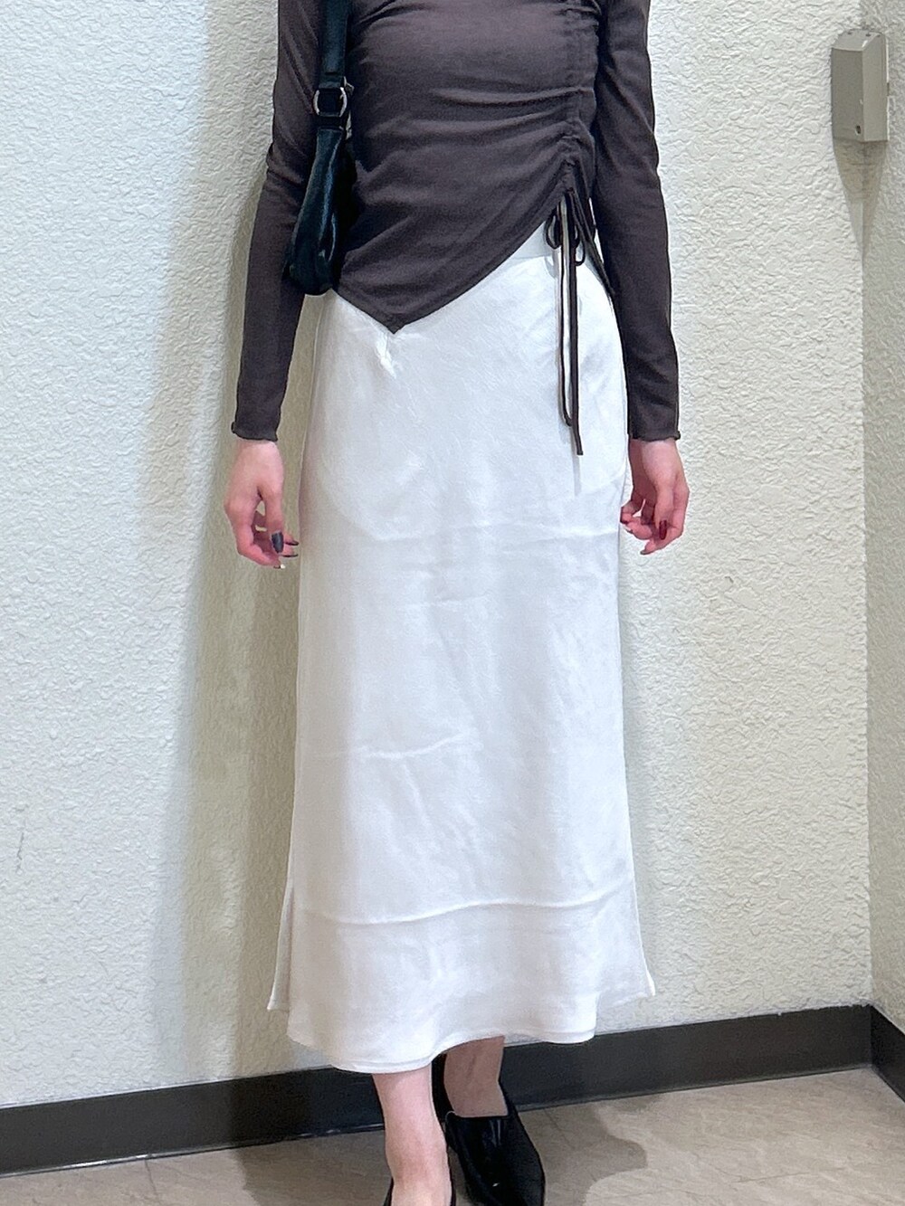 ブラウン系のTシャツ/カットソー、ホワイト系のスカート、ブラック系のパンプスを着用したレディースの秋コーディネートの5枚目の写真