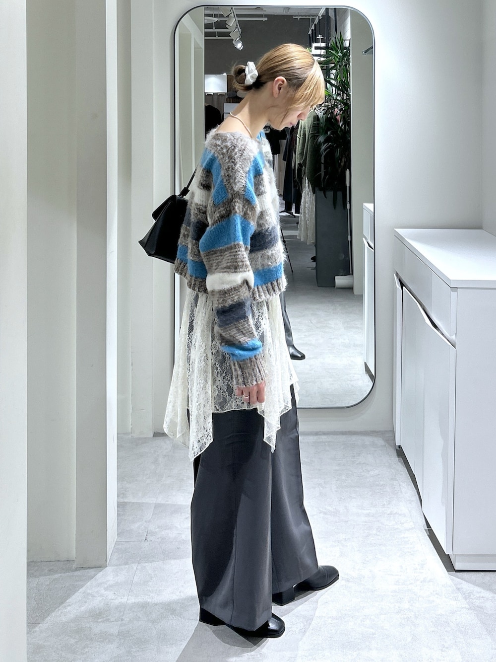 ブラウン系のニット/セーター、ホワイト系のスカート、グレー系のスラックスを着用したレディースの秋コーディネートの2枚目の写真