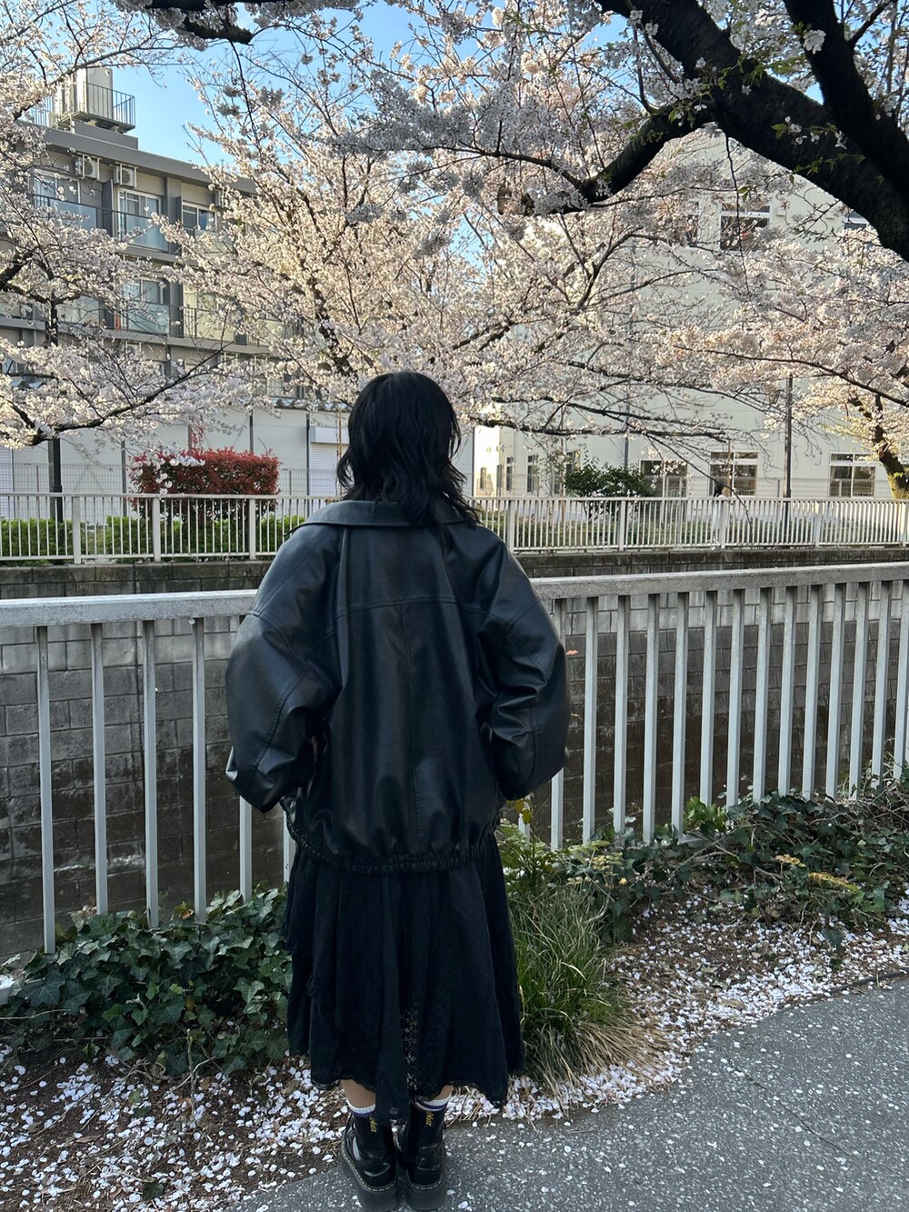 ブラック系のワンピース、ブラック系のブーツ、ブラック系のジャケット/アウターを着用したレディースの春コーディネートの2枚目の写真