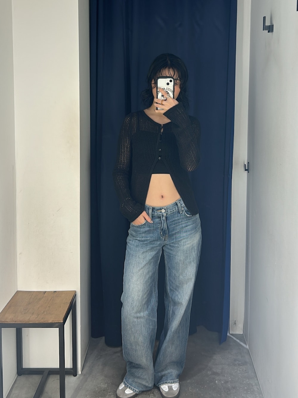 ブルー系のデニムパンツ、ブラック系のトップス、ホワイト系のスニーカーを着用したレディースの春コーディネートの2枚目の写真