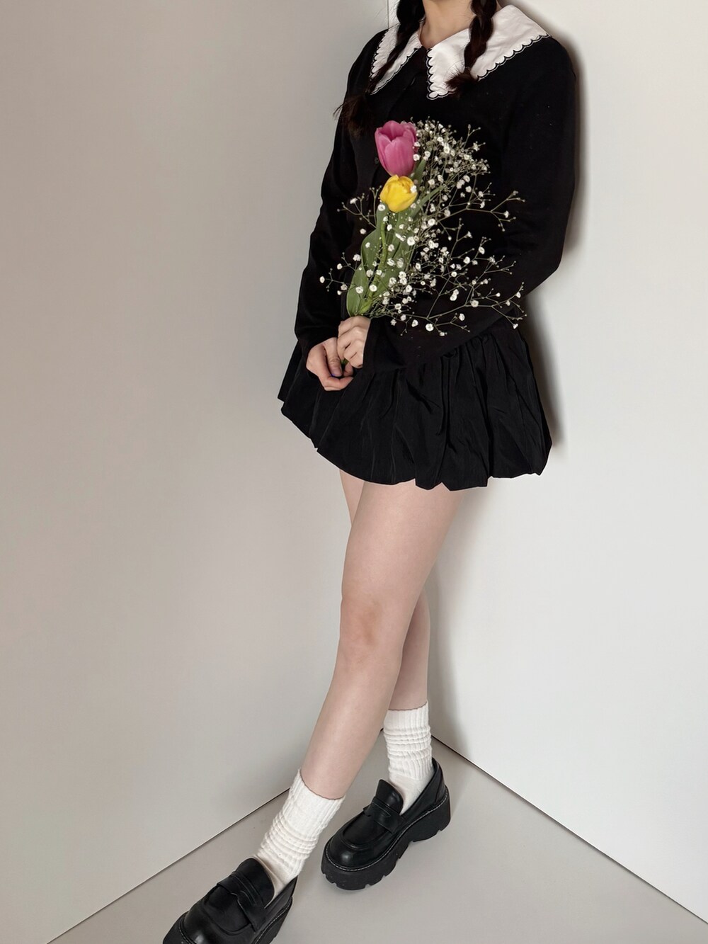 ブラック系のカーディガン/ボレロ、ブラック系のスカート、ホワイト系のシャツ/ブラウスを着用したレディースの春コーディネートの2枚目の写真