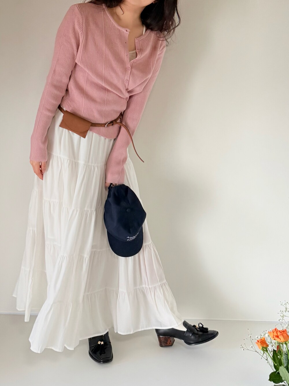 ホワイト系のスカート、ピンク系のカーディガン/ボレロ、ブラウン系のベルトを着用したレディースの春コーディネートの3枚目の写真