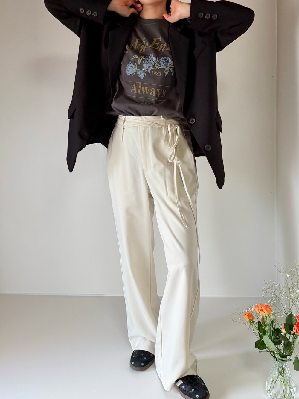 グレー系のTシャツ/カットソー、ホワイト系のスラックス、ブラック系のスニーカーを着用したレディースの春コーディネートの2枚目の写真