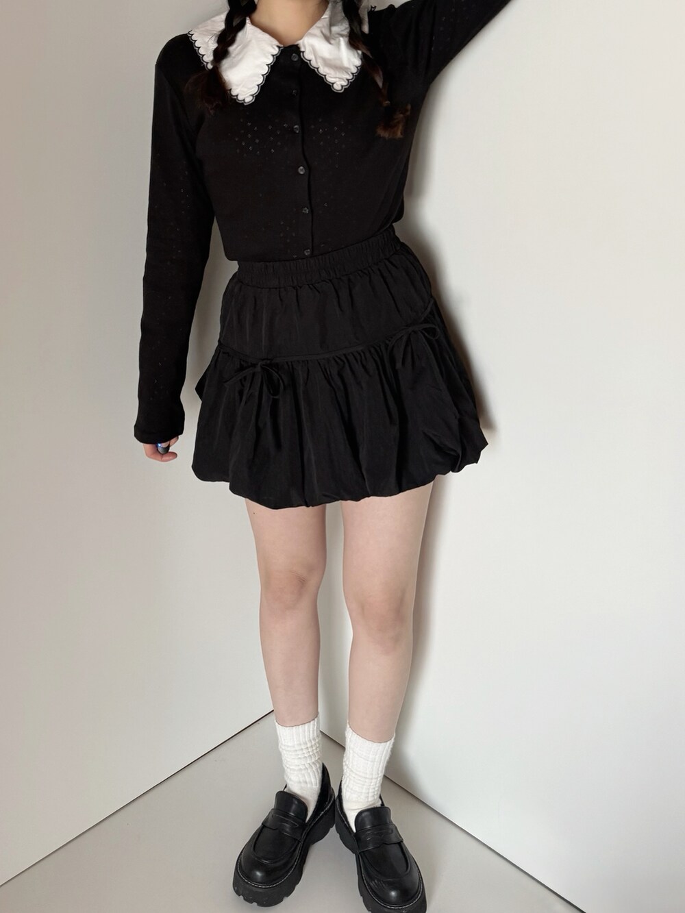 ブラック系のカーディガン/ボレロ、ブラック系のスカート、ホワイト系のシャツ/ブラウスを着用したレディースの春コーディネートの4枚目の写真