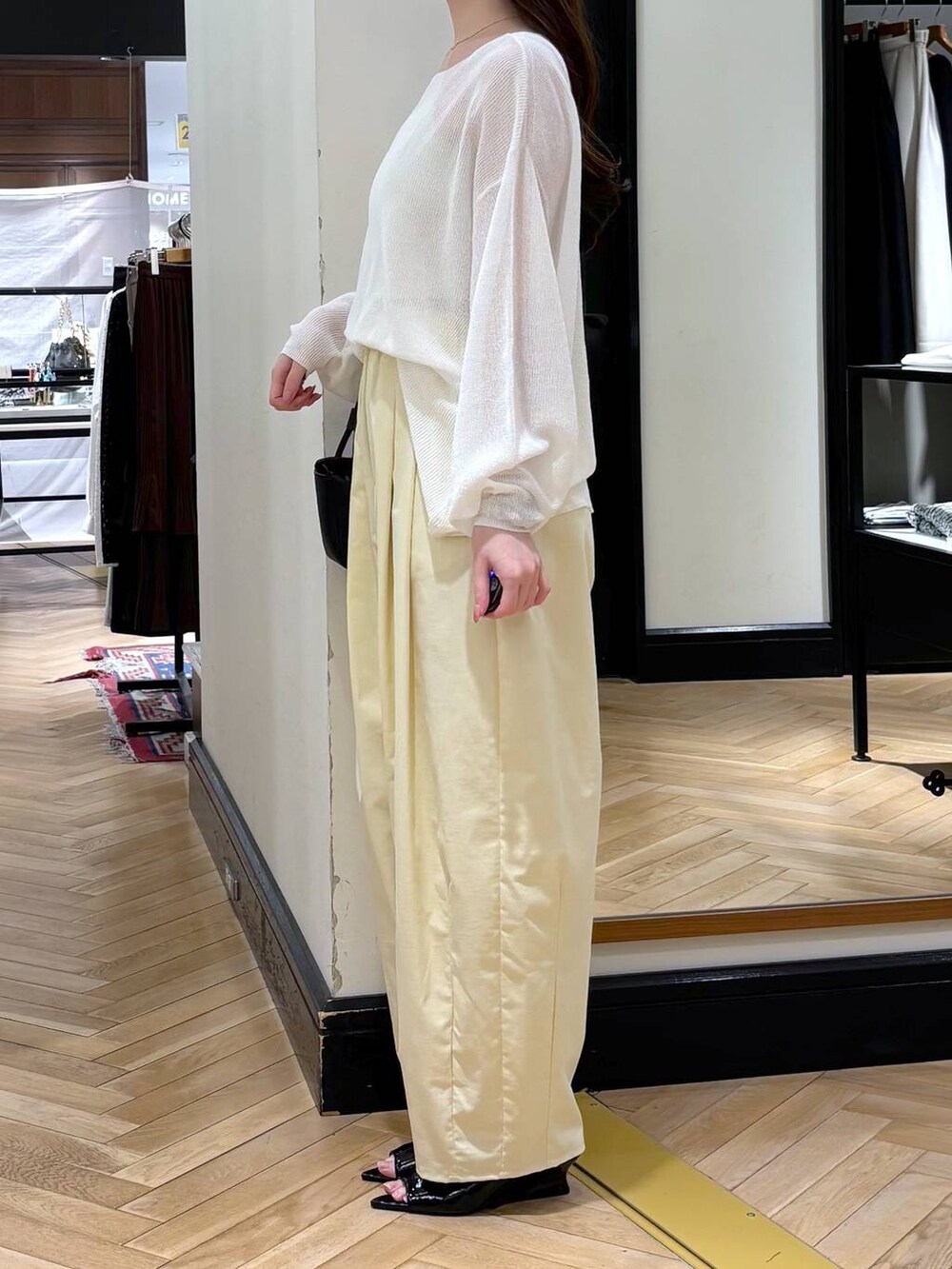 ブラック系のショルダーバッグ、ブラック系のサンダル、ホワイト系のニット/セーターを着用したレディースの春コーディネートの3枚目の写真