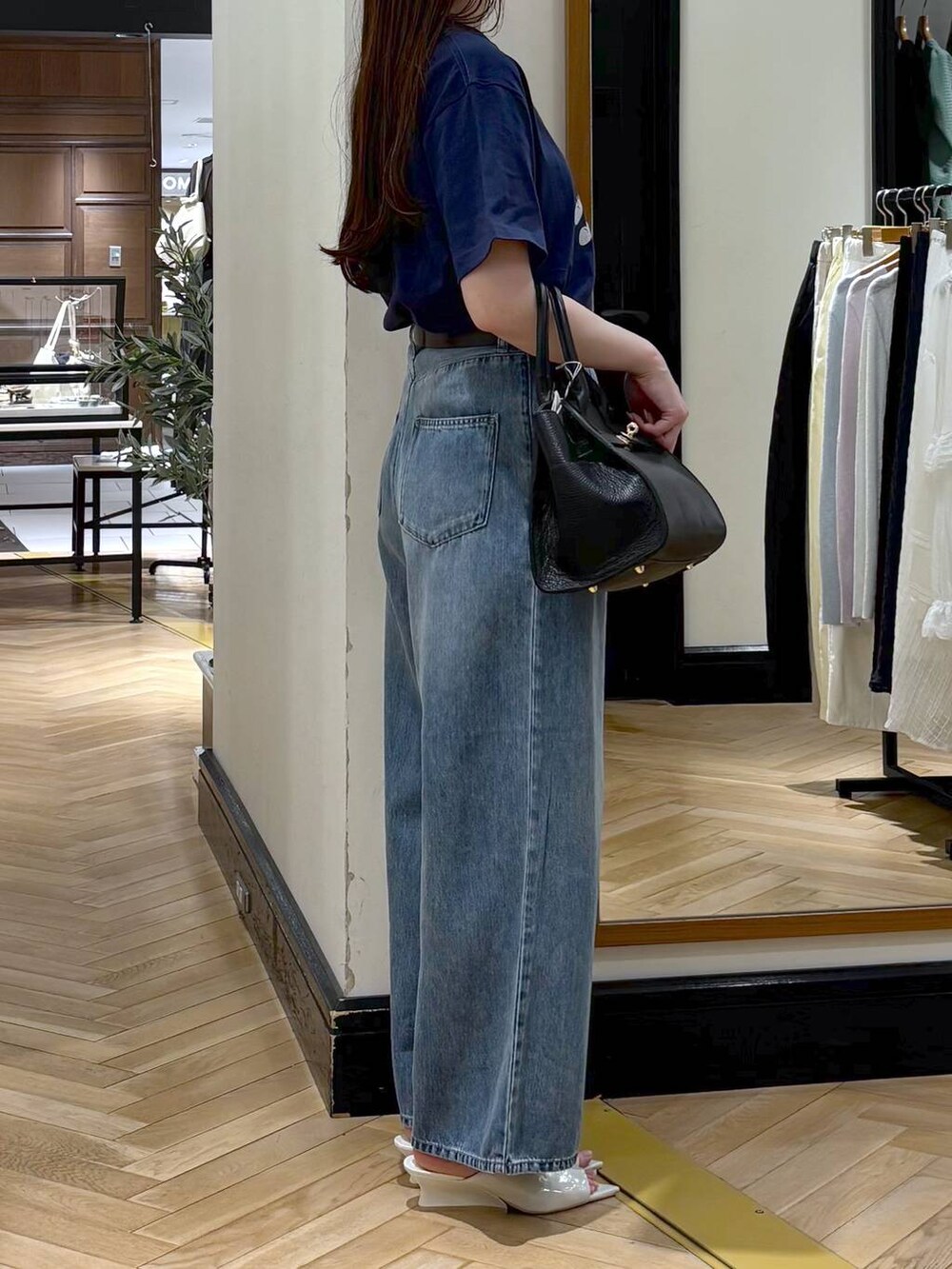 ブラック系のショルダーバッグ、ブルー系のデニムパンツ、ホワイト系のサンダルを着用したレディースの春コーディネートの2枚目の写真