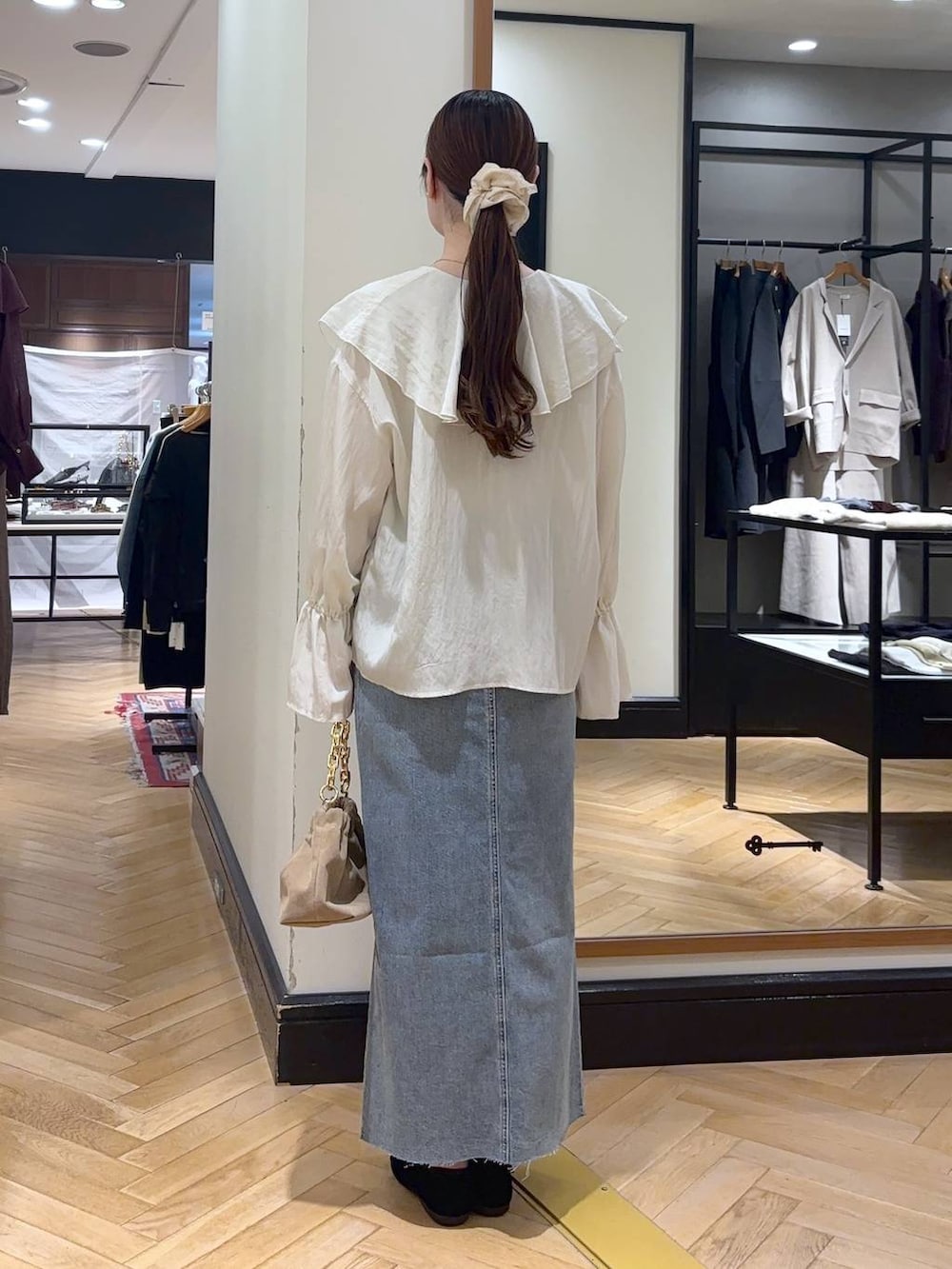 ブルー系のデニムスカート、ブラック系のバレエシューズ、ベージュ系のショルダーバッグを着用したレディースの秋コーディネートの6枚目の写真