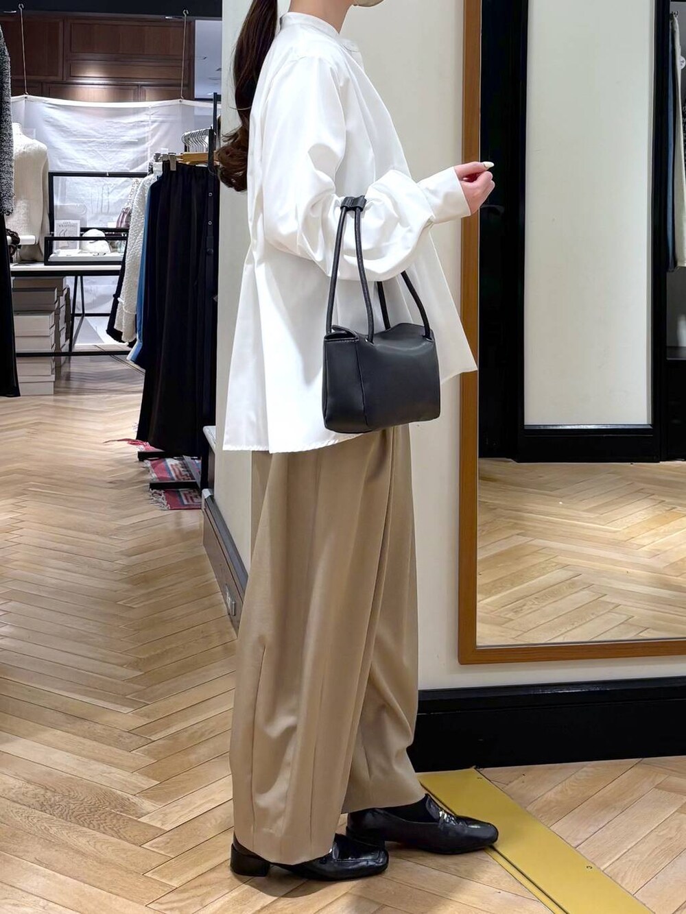 ベージュ系のスラックス、ブラック系のローファー、ホワイト系のTシャツ/カットソーを着用したレディースの冬コーディネートの4枚目の写真