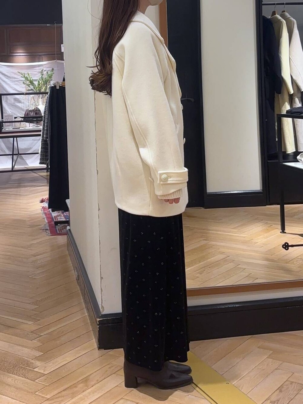 ホワイト系のピーコート、ブラウン系のブーツ、ホワイト系のニット/セーターを着用したレディースの冬コーディネートの2枚目の写真