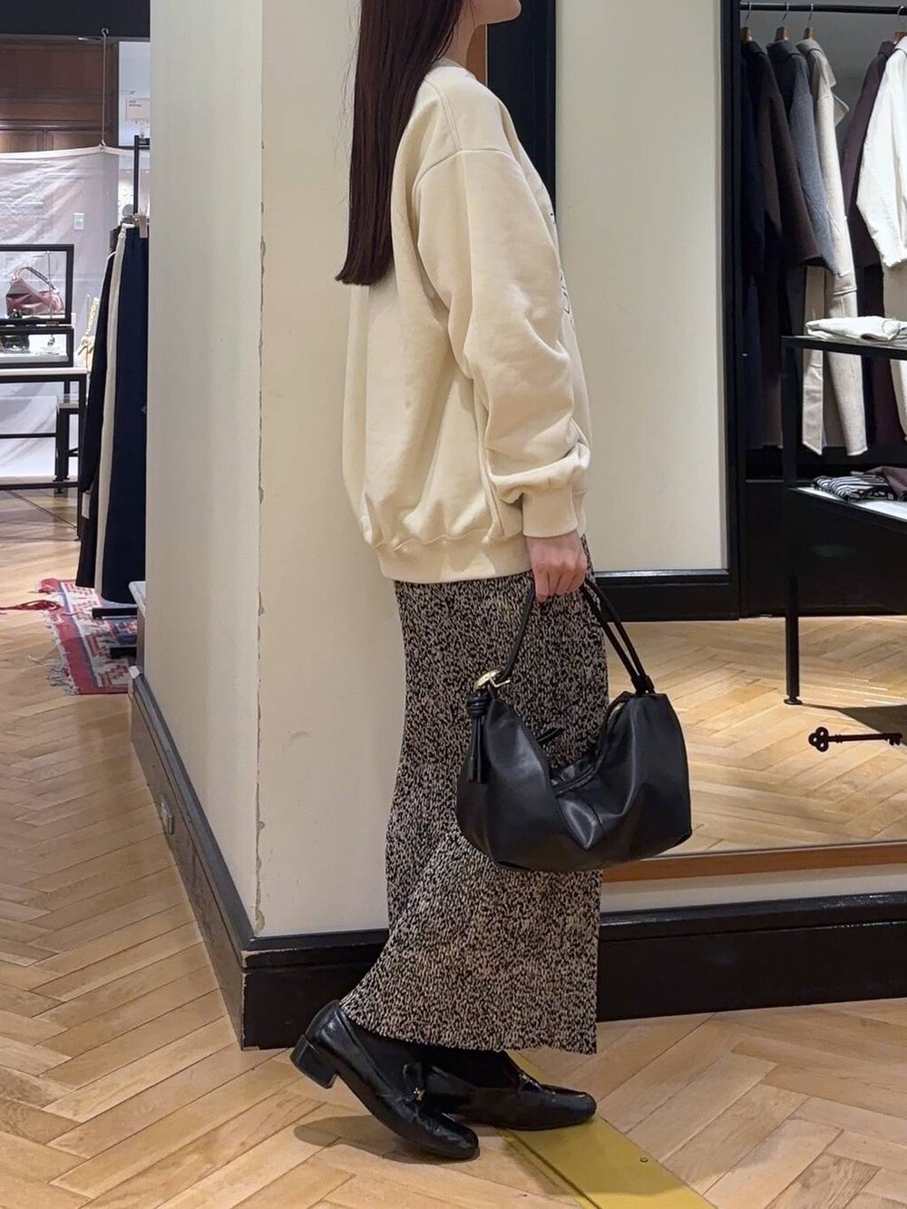 ブラック系のローファー、ベージュ系のスカート、ブラック系のショルダーバッグを着用したレディースの秋コーディネートの2枚目の写真