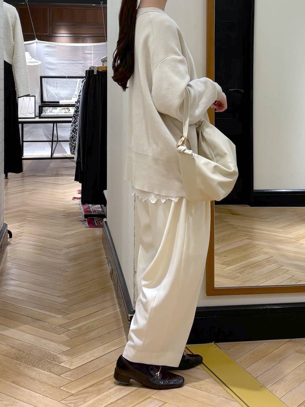 ホワイト系のスラックス、ブラック系のローファー、ホワイト系のカーディガン/ボレロを着用したレディースの冬コーディネートの3枚目の写真