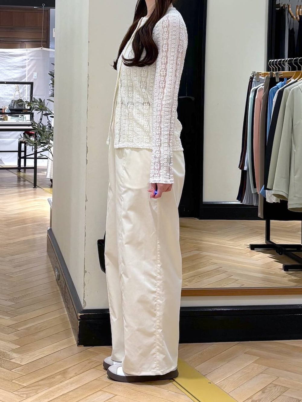 ホワイト系のスラックス、ブラック系のショルダーバッグ、ホワイト系のカーディガン/ボレロを着用したレディースの春コーディネートの5枚目の写真