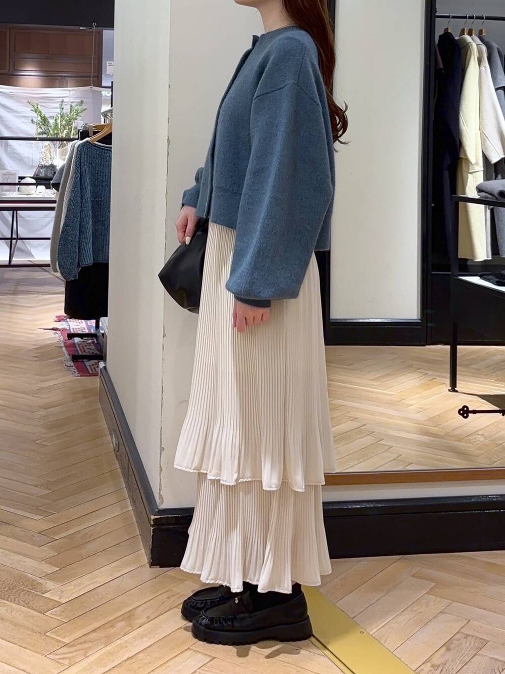 ホワイト系のスカート、ブルー系のカーディガン/ボレロ、ブラック系のショルダーバッグを着用したレディースの冬コーディネートの3枚目の写真