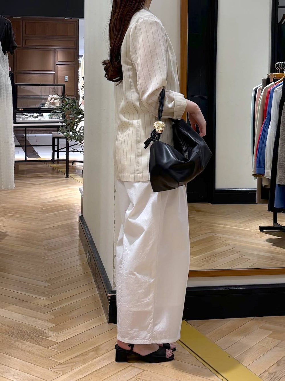 ベージュ系のテーラードジャケット、ブラック系のショルダーバッグ、ホワイト系のタンクトップを着用したレディースの春コーディネートの2枚目の写真