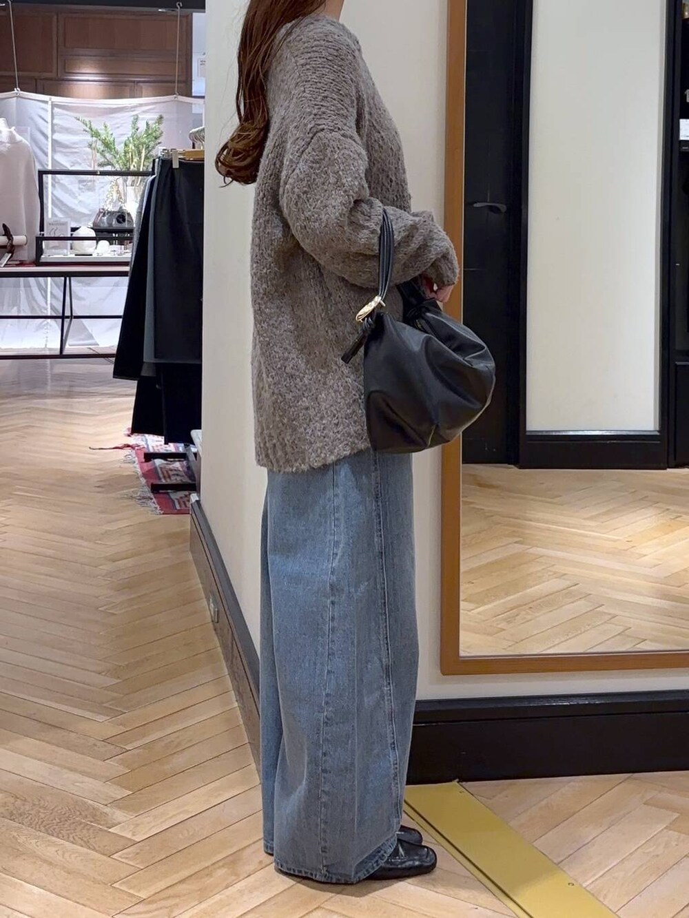 ブルー系のデニムパンツ、ブラック系のローファー、ブラック系のショルダーバッグを着用したレディースの冬コーディネートの2枚目の写真