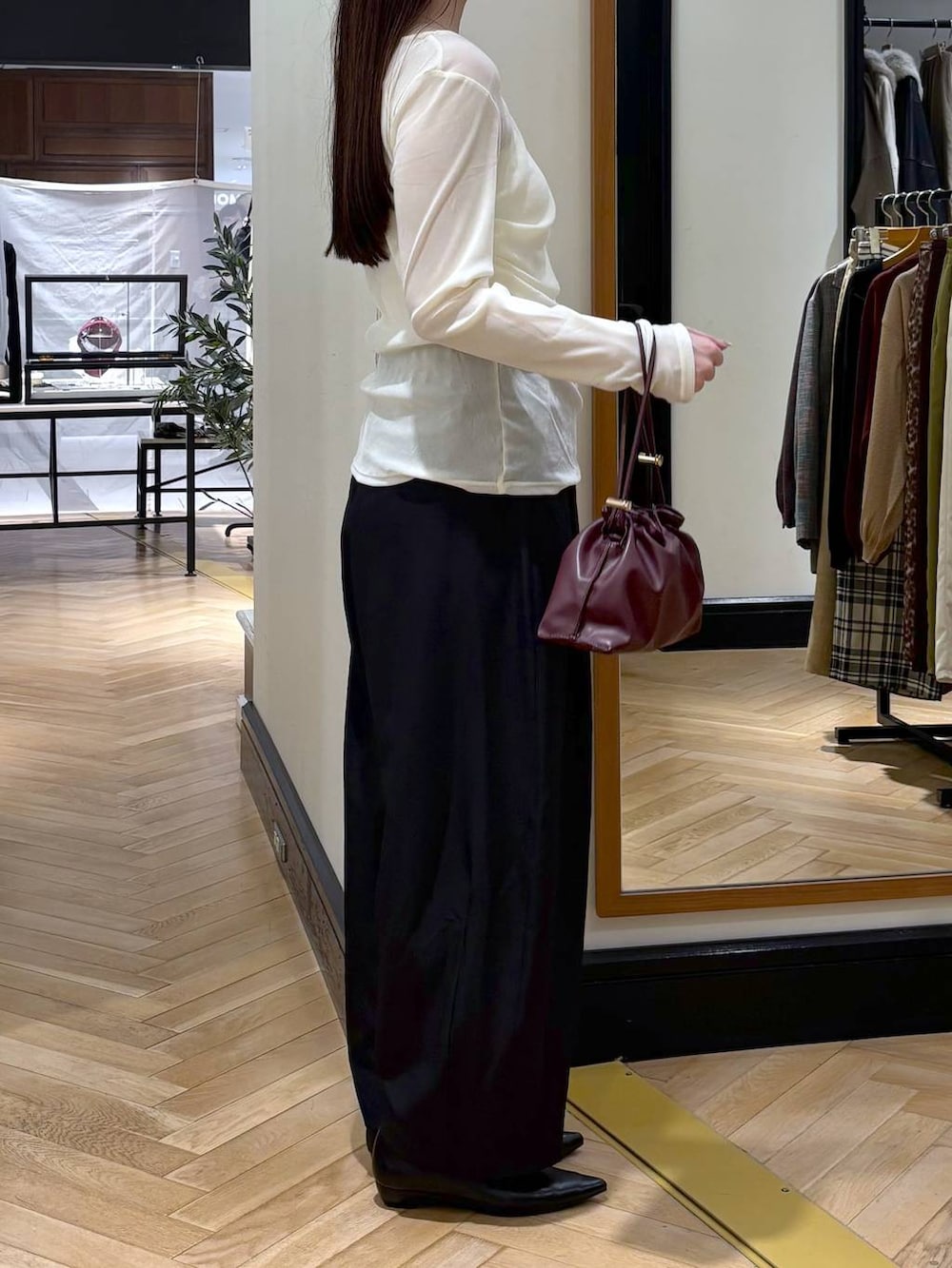 レッド系のショルダーバッグ、ブラック系のパンプス、ホワイト系のキャミソールを着用したレディースの秋コーディネートの2枚目の写真