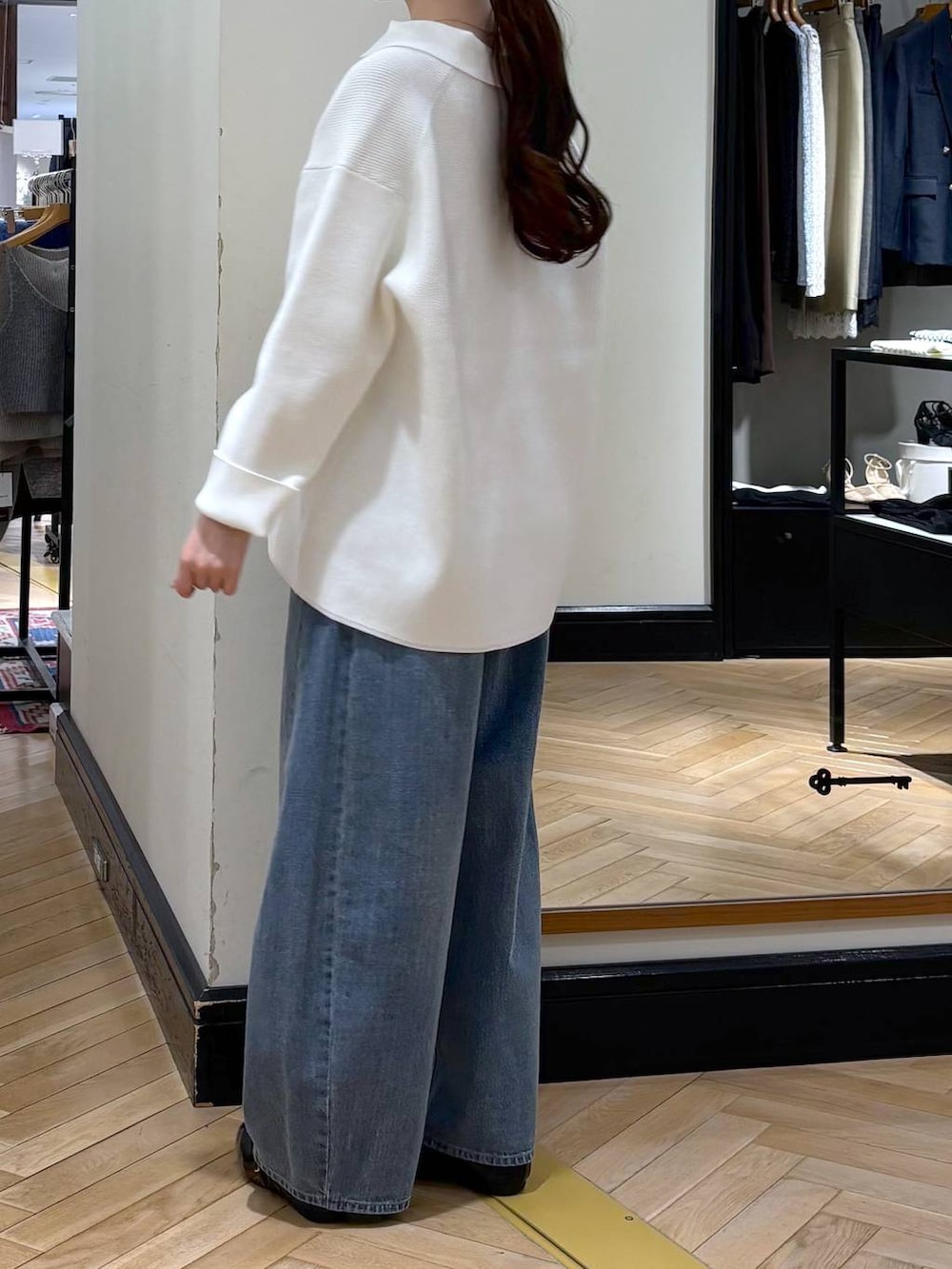 ブルー系のデニムパンツ、ブラック系のショルダーバッグ、ホワイト系のニット/セーターを着用したレディースの冬コーディネートの4枚目の写真