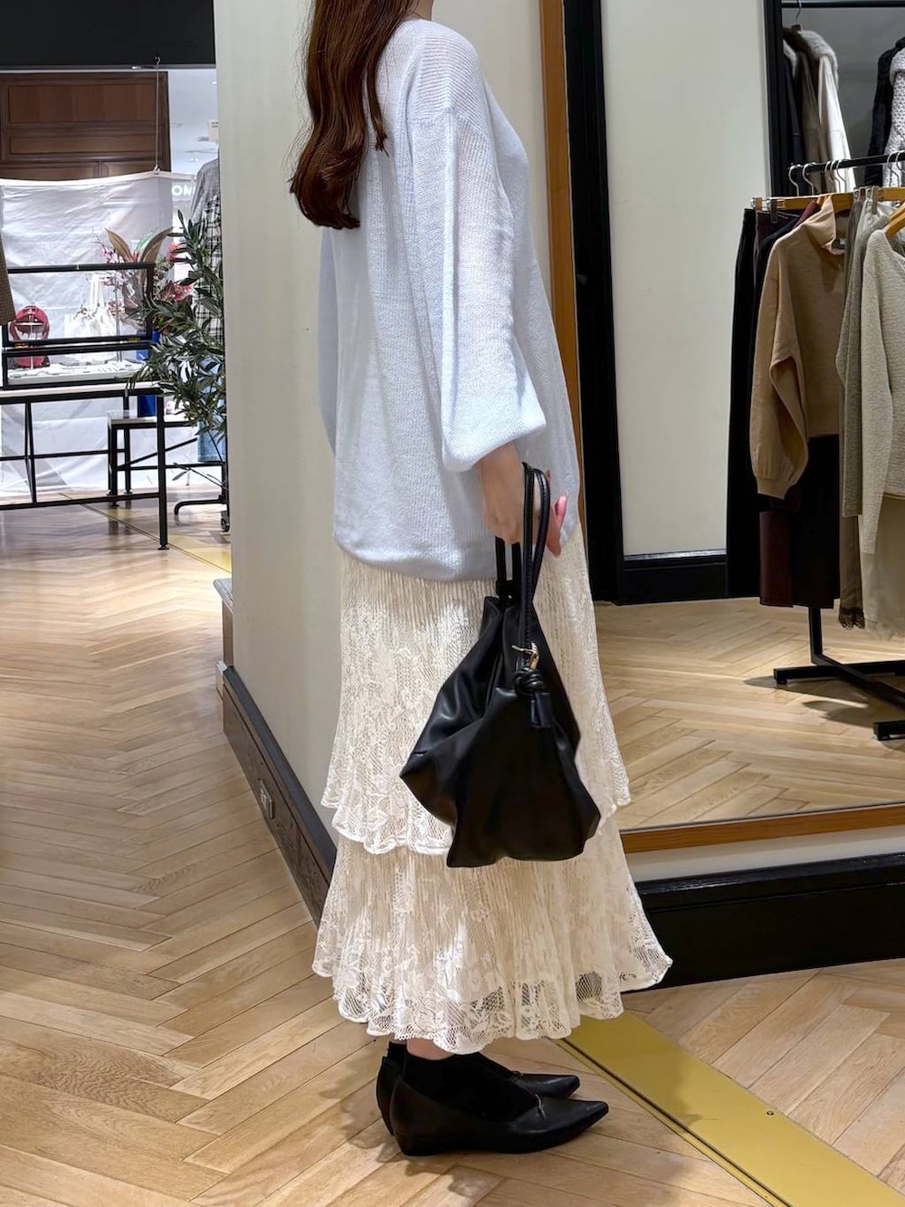 ブラック系のパンプス、ホワイト系のスカート、ブラック系のショルダーバッグを着用したレディースの秋コーディネートの2枚目の写真