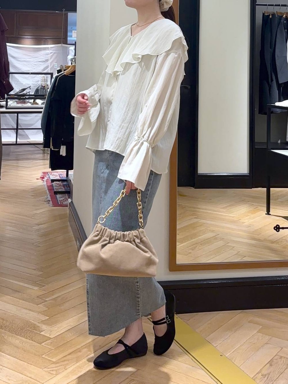 ブルー系のデニムスカート、ブラック系のバレエシューズ、ベージュ系のショルダーバッグを着用したレディースの秋コーディネートの3枚目の写真