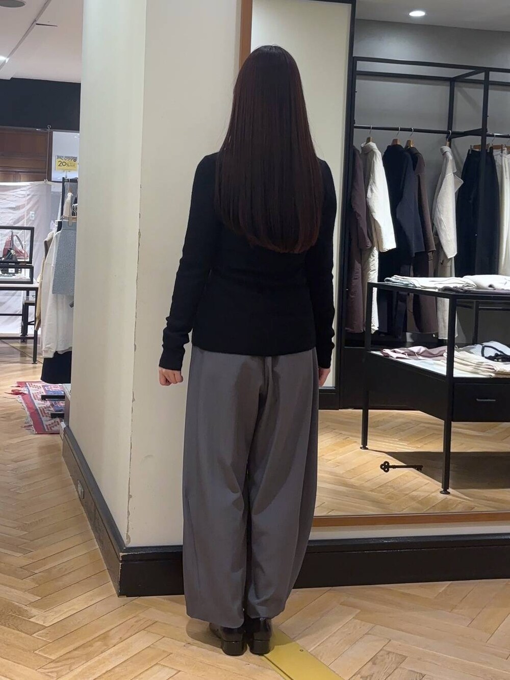 グレー系のスラックス、ブラック系のローファー、ブラック系のボストンバッグを着用したレディースの秋コーディネートの4枚目の写真