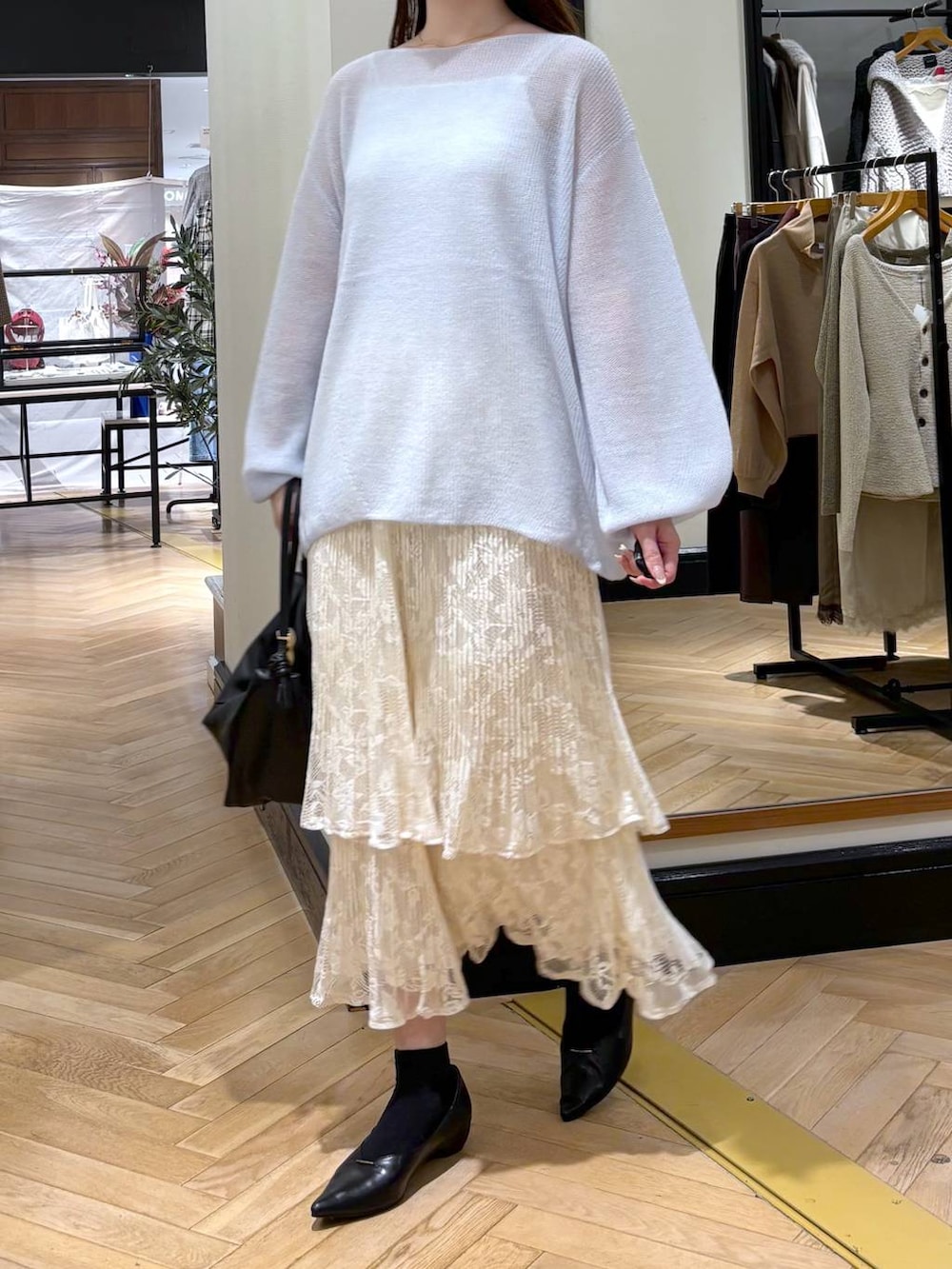 ブラック系のパンプス、ホワイト系のスカート、ブラック系のショルダーバッグを着用したレディースの秋コーディネートの3枚目の写真