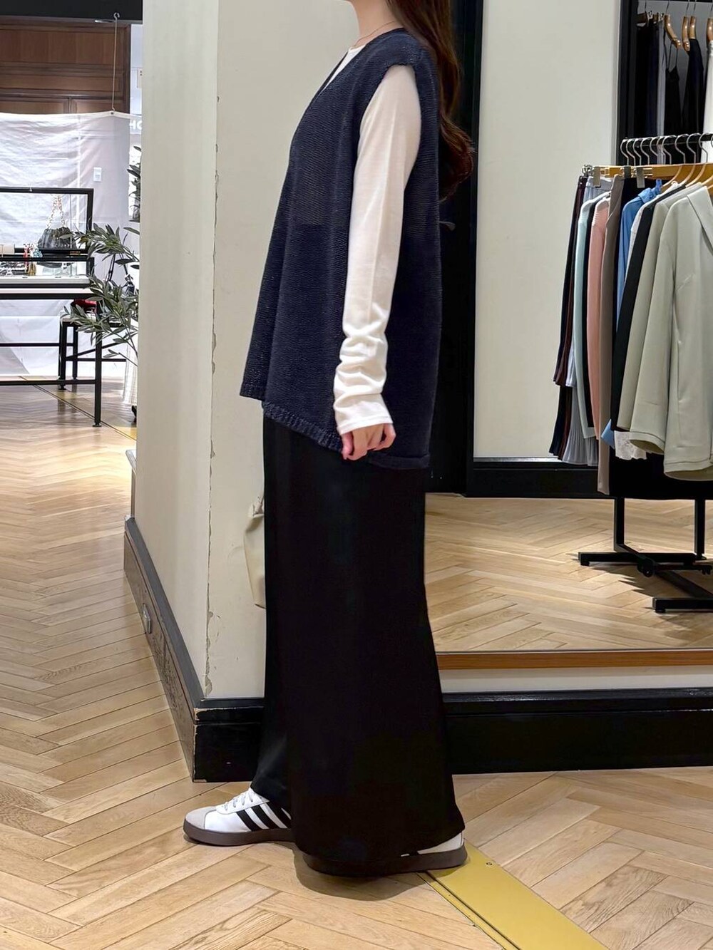 ブラック系のスカート、ブルー系のニット/セーター、ベージュ系のショルダーバッグを着用したレディースの春コーディネートの3枚目の写真