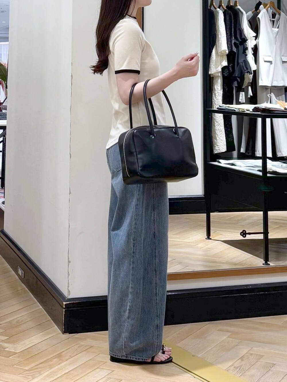 ブルー系のデニムパンツ、ブラック系のボストンバッグ、ブラック系のサンダルを着用したレディースの夏コーディネートの2枚目の写真