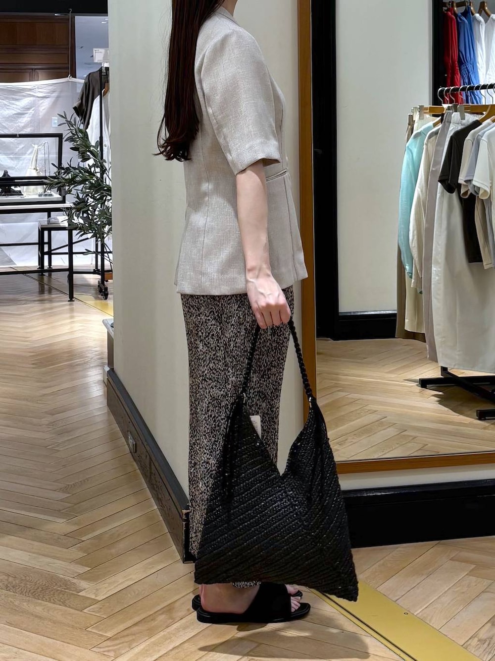 ベージュ系のスカート、ベージュ系のノーカラージャケット、ブラック系のサンダルを着用したレディースの春コーディネートの2枚目の写真