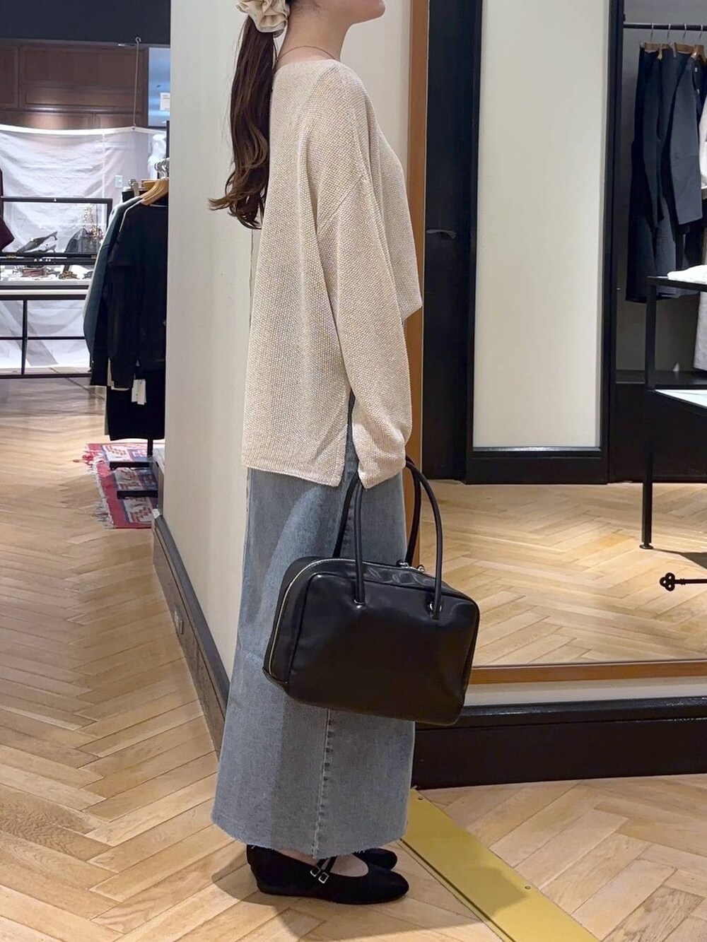 ブラック系のボストンバッグ、ブルー系のデニムスカート、ブラック系のバレエシューズを着用したレディースの秋コーディネートの4枚目の写真