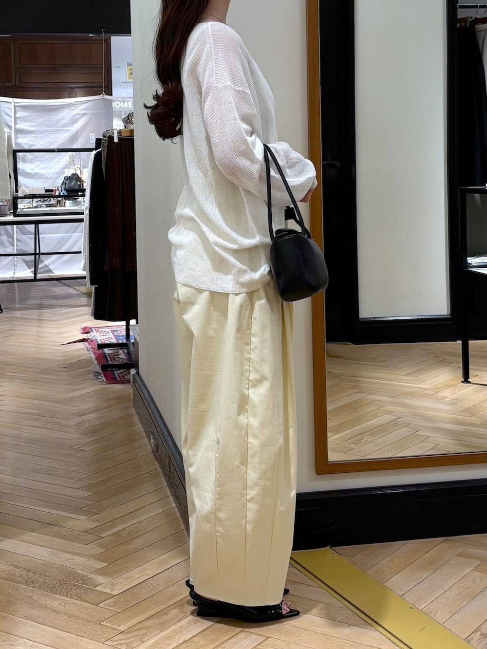 ブラック系のショルダーバッグ、ブラック系のサンダル、ホワイト系のニット/セーターを着用したレディースの春コーディネートの2枚目の写真