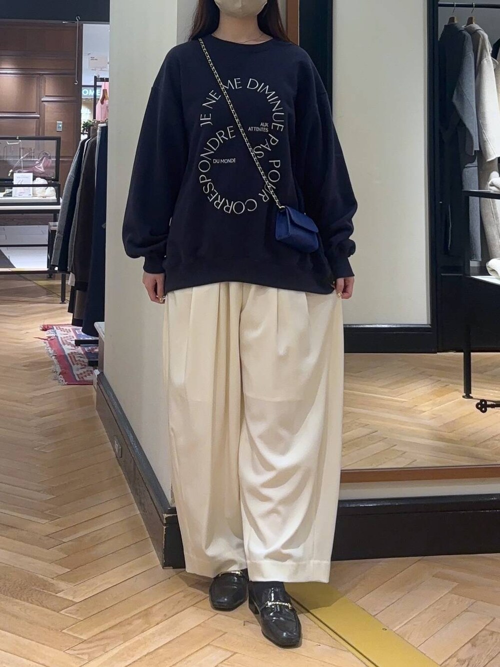 ホワイト系のスラックス、ブラック系のローファー、ブルー系のスウェットを着用したレディースの秋コーディネートの2枚目の写真