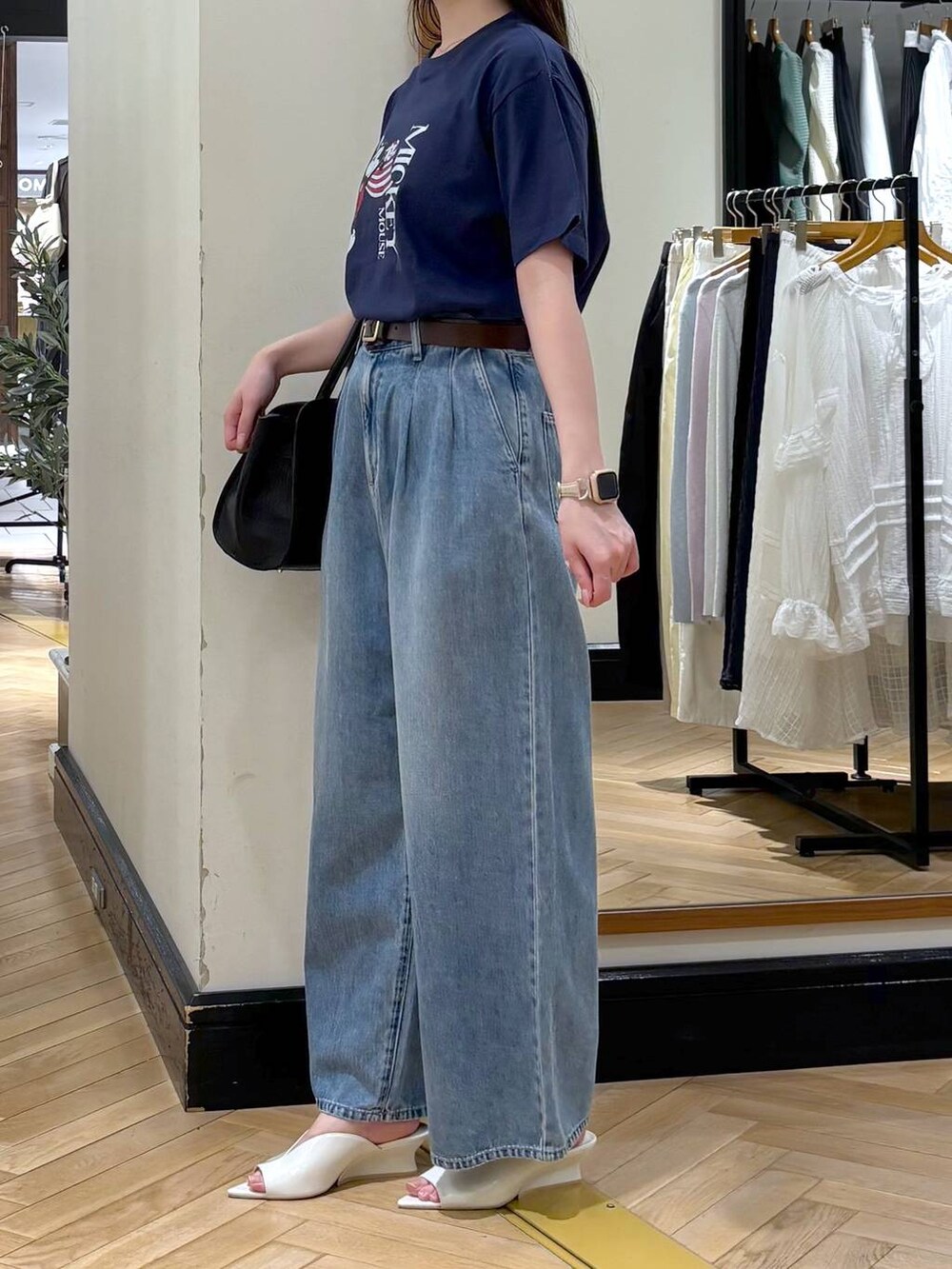 ブラック系のショルダーバッグ、ブルー系のデニムパンツ、ホワイト系のサンダルを着用したレディースの春コーディネートの3枚目の写真