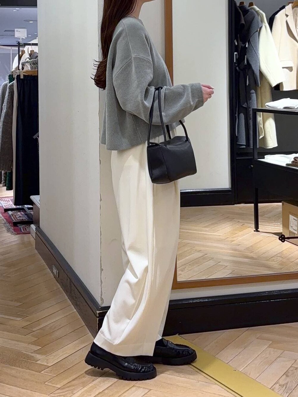 ホワイト系のスラックス、グリーン系のニット/セーター、ブラック系のローファーを着用したレディースの冬コーディネートの2枚目の写真