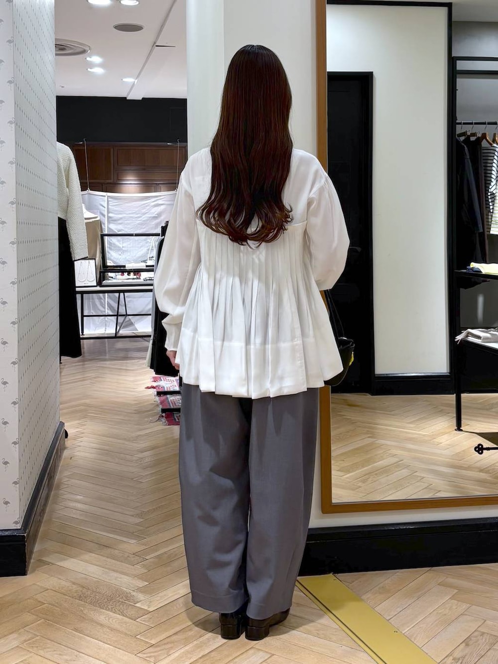 グレー系のスラックス、ブラック系のローファー、ブラック系のショルダーバッグを着用したレディースの冬コーディネートの5枚目の写真