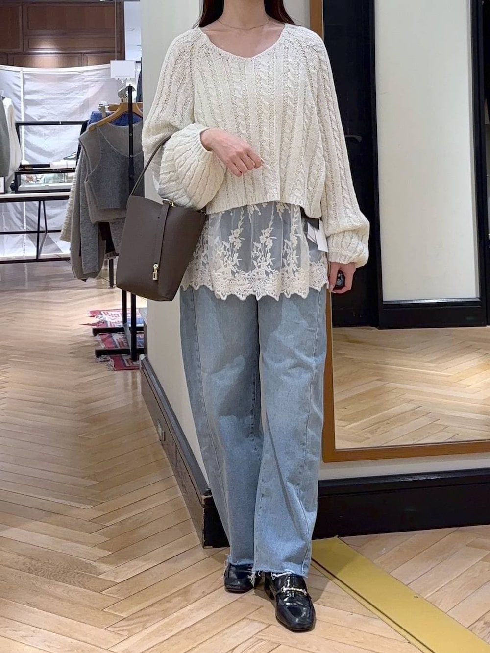 ブラック系のローファー、ホワイト系のチュニック、ブルー系のデニムパンツを着用したレディースの冬コーディネートの2枚目の写真