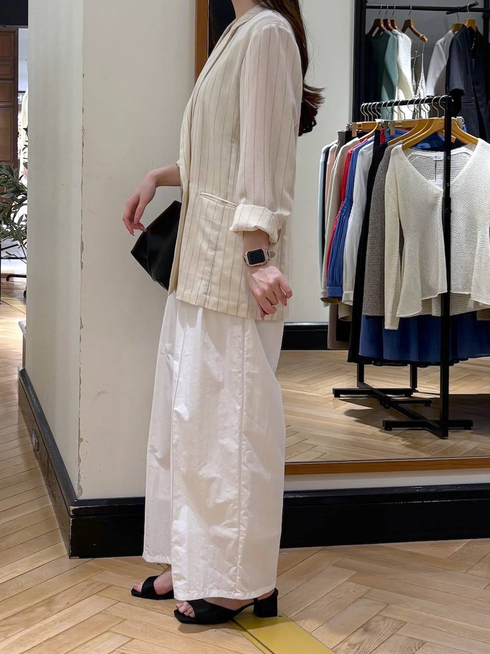 ベージュ系のテーラードジャケット、ブラック系のショルダーバッグ、ホワイト系のタンクトップを着用したレディースの春コーディネートの3枚目の写真