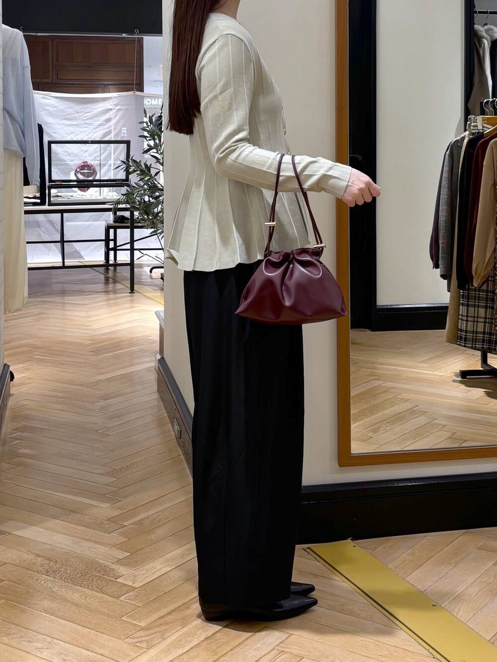 レッド系のショルダーバッグ、ベージュ系のカーディガン/ボレロ、ブラック系のパンプスを着用したレディースの秋コーディネートの2枚目の写真