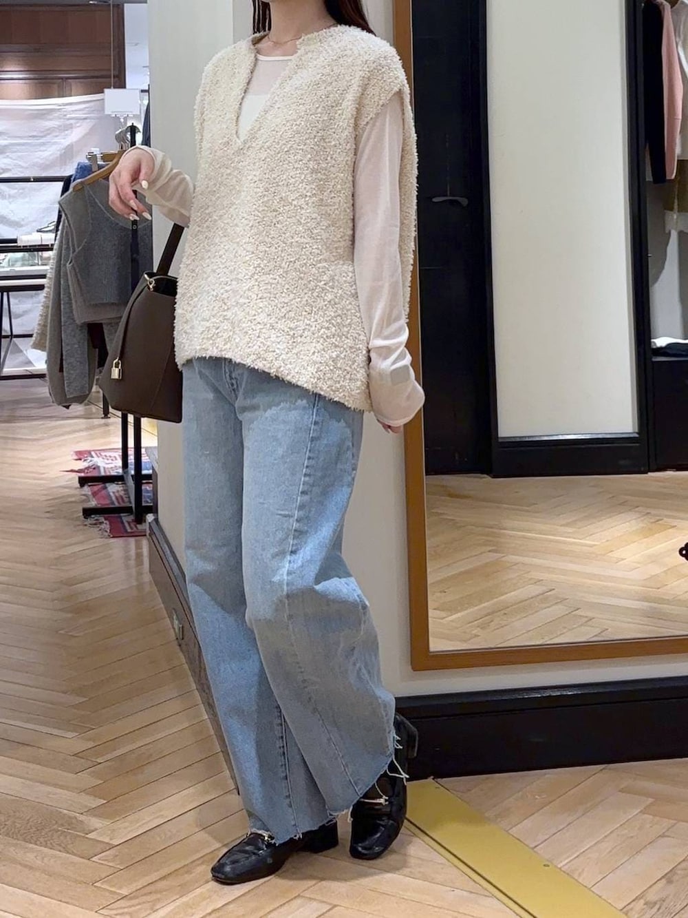 ブラック系のローファー、ブルー系のデニムパンツ、ホワイト系のベストを着用したレディースの冬コーディネートの3枚目の写真