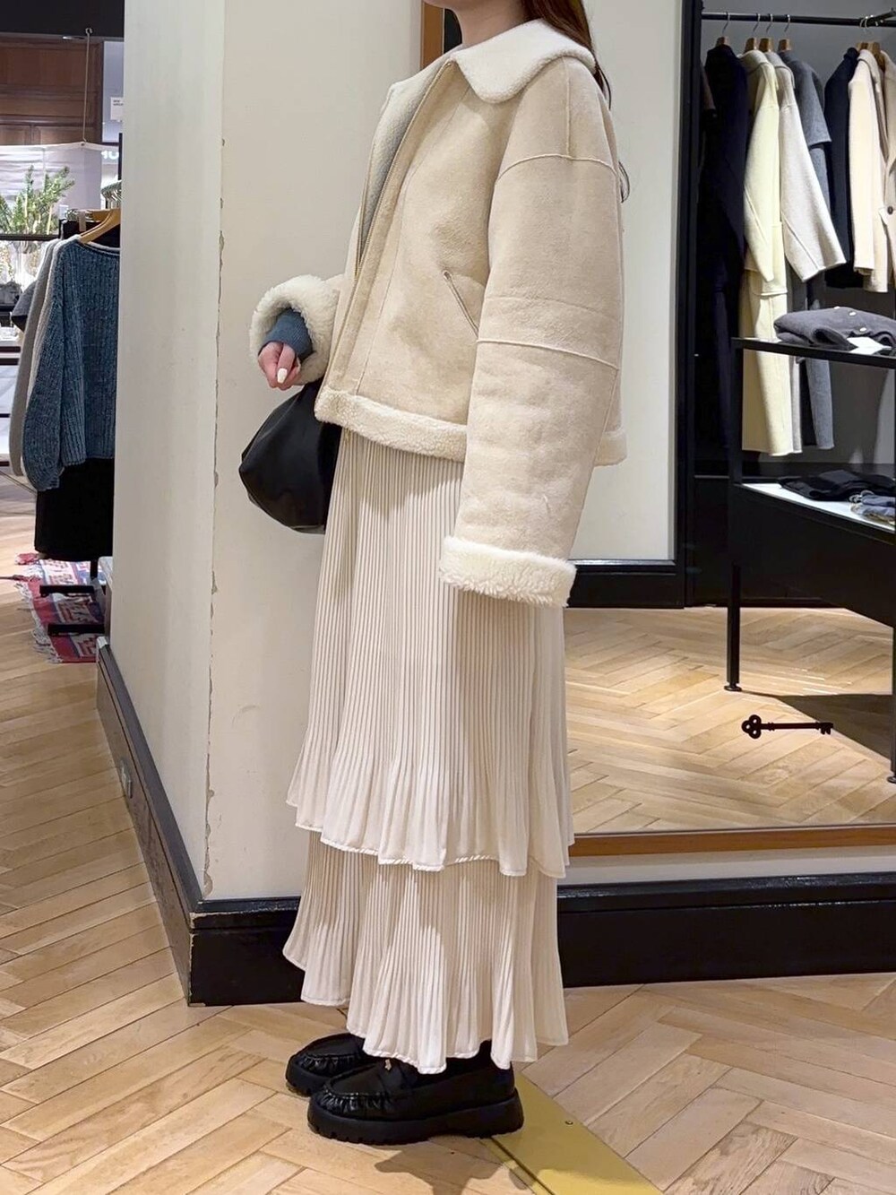 ホワイト系のスカート、ブルー系のカーディガン/ボレロ、ブラック系のショルダーバッグを着用したレディースの冬コーディネートの3枚目の写真