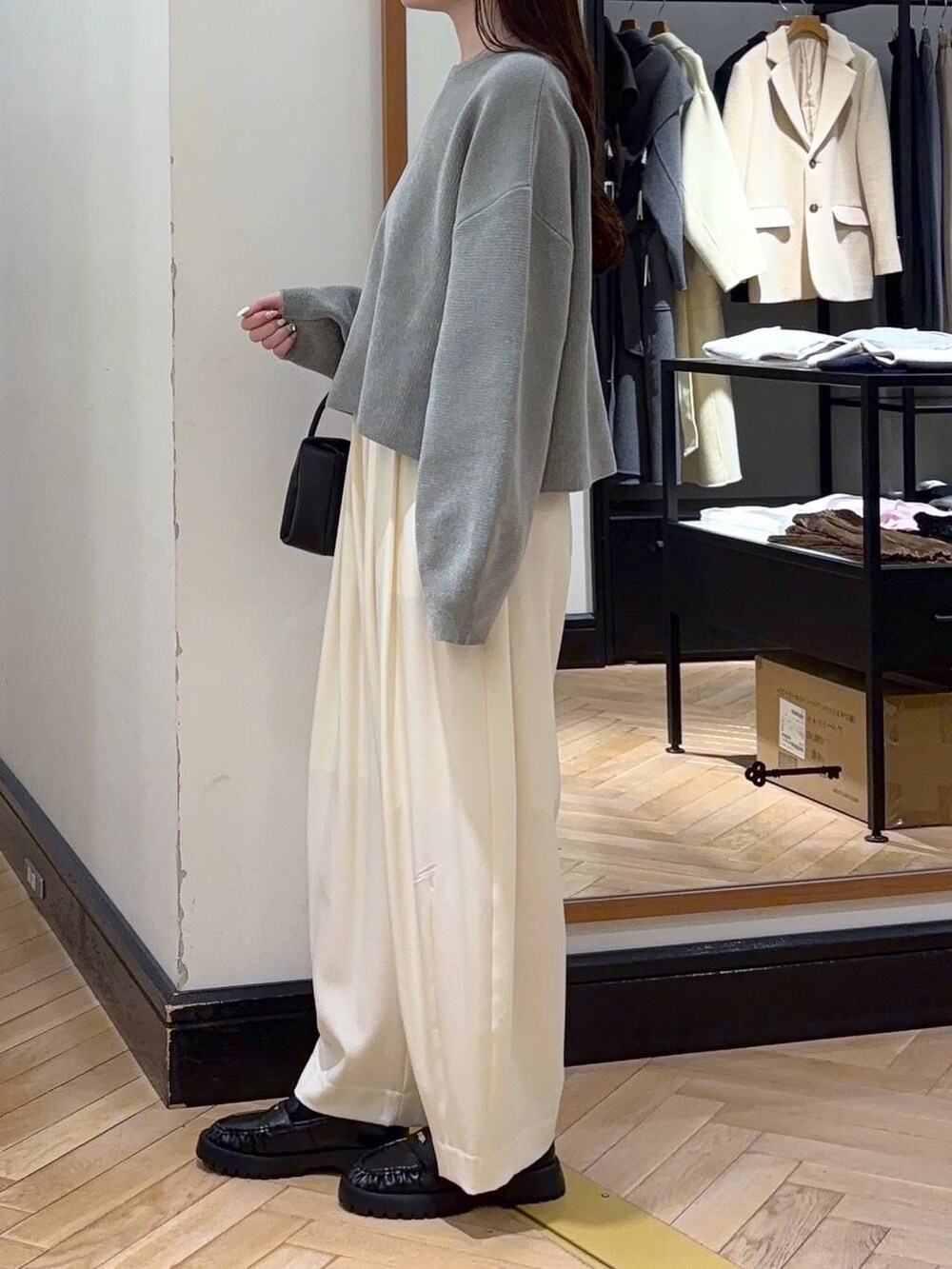 ホワイト系のスラックス、グリーン系のニット/セーター、ブラック系のローファーを着用したレディースの冬コーディネートの3枚目の写真