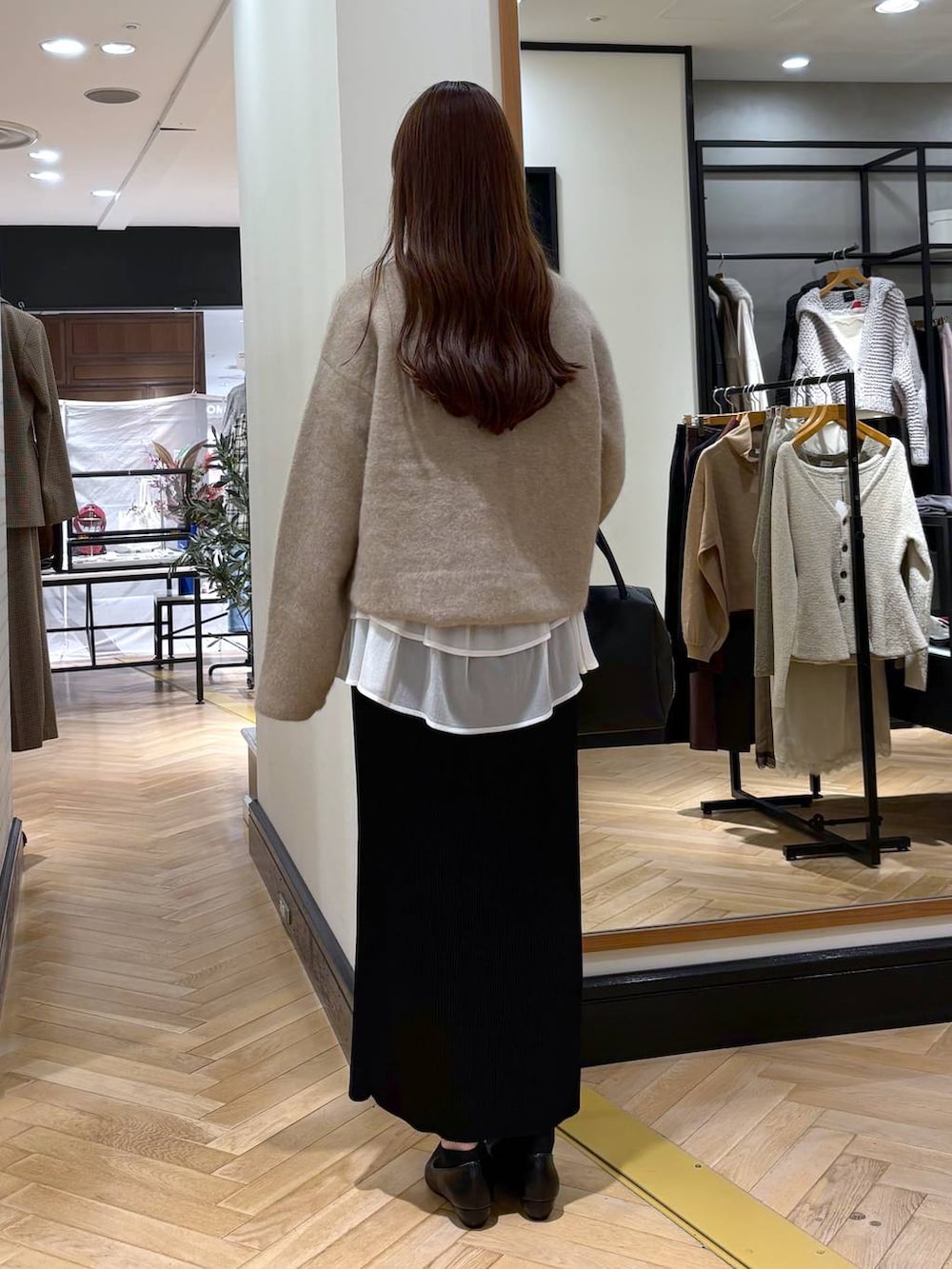ブラック系のパンプス、ベージュ系のTシャツ/カットソー、ブラック系のスカートを着用したレディースの秋コーディネートの4枚目の写真