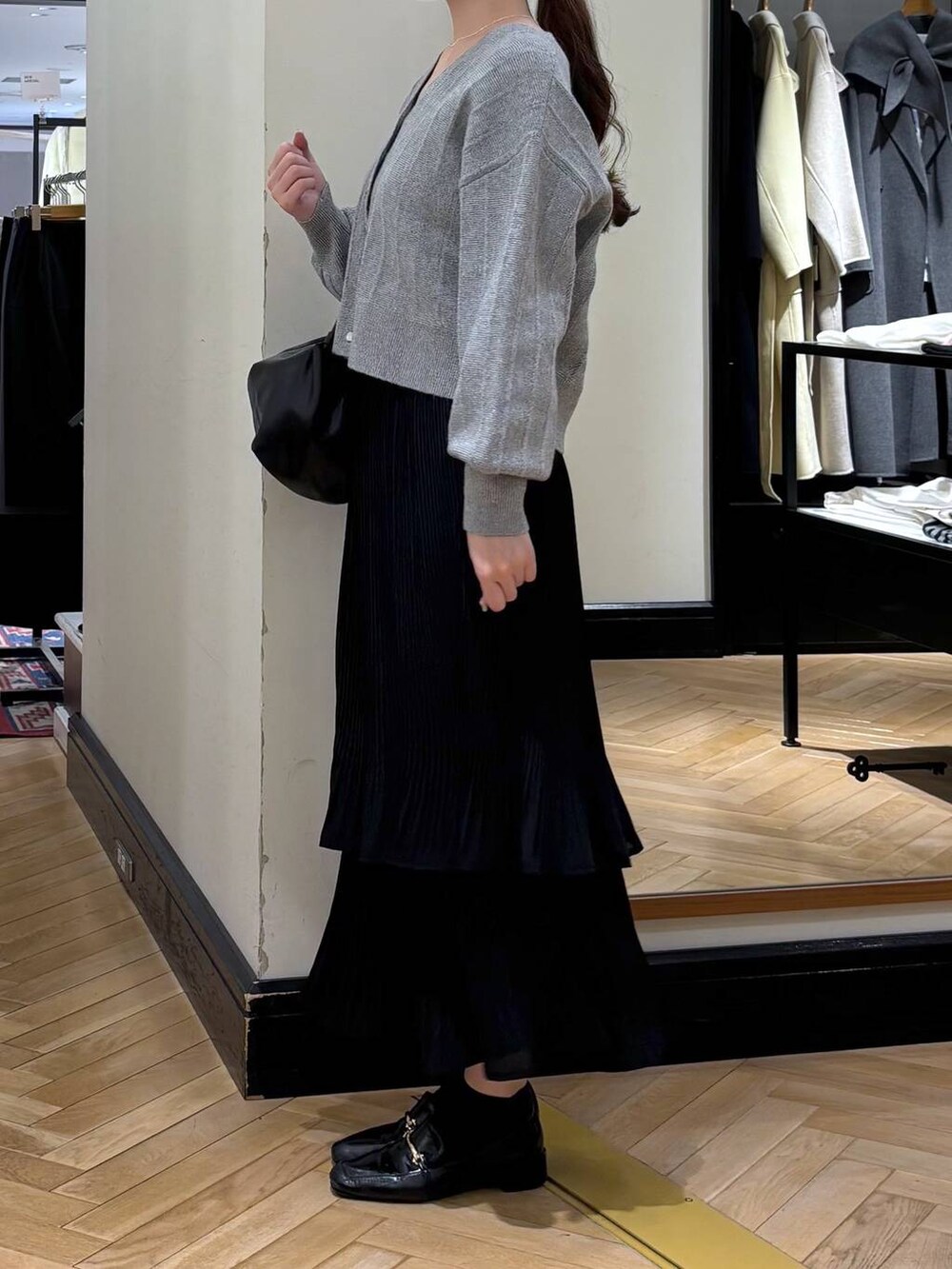 ブラック系のスカート、ブラック系のローファー、ブラック系のショルダーバッグを着用したレディースの冬コーディネートの3枚目の写真