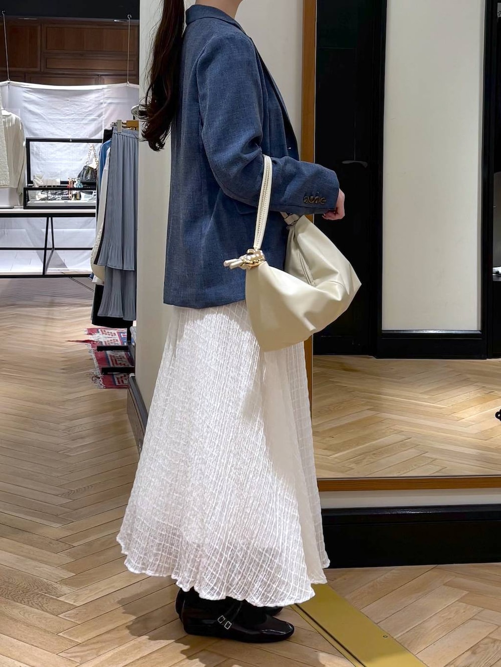 ベージュ系のショルダーバッグ、ブルー系のノーカラージャケット、ブルー系のTシャツ/カットソーを着用したレディースの春コーディネートの2枚目の写真