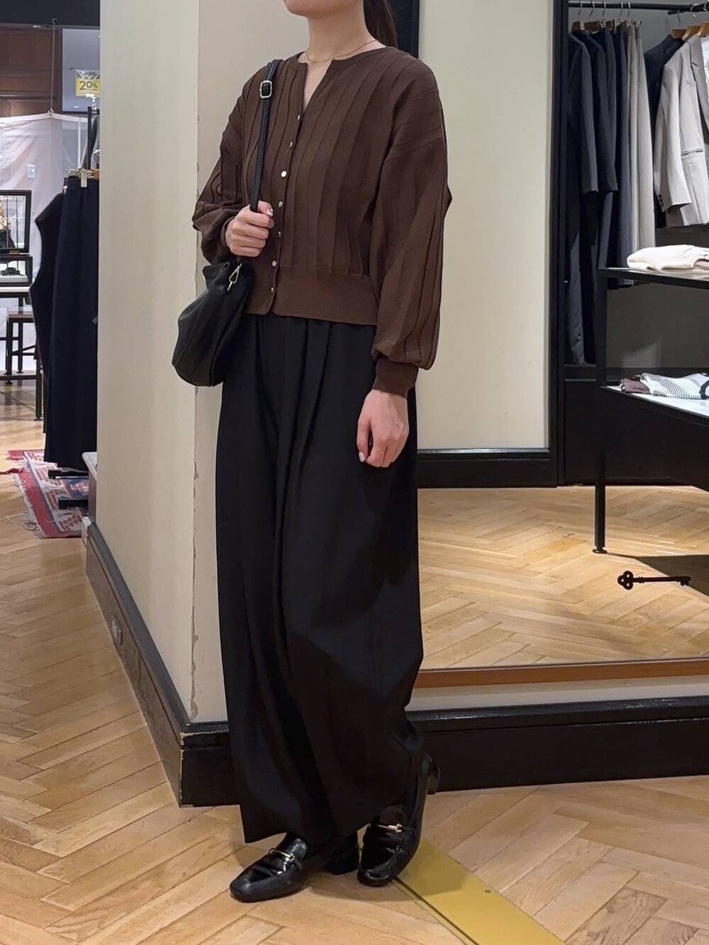 ブラック系のハンドバッグ、ブラウン系のカーディガン/ボレロ、ブラック系のローファーを着用したレディースの秋コーディネートの3枚目の写真