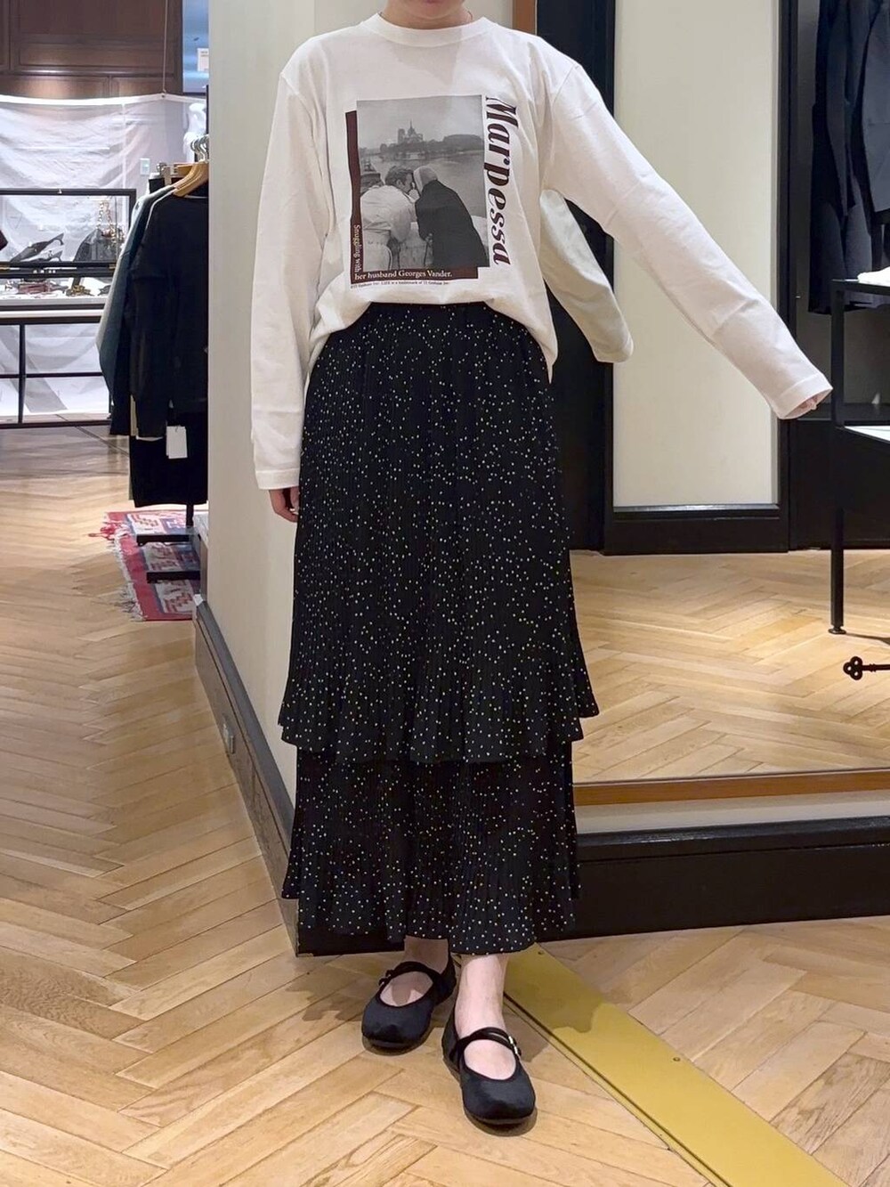 グレー系のスカート、ブラック系のバレエシューズ、ホワイト系のTシャツ/カットソーを着用したレディースの秋コーディネートの2枚目の写真